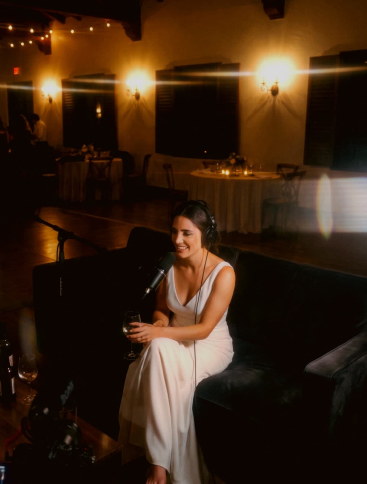 La novia al micrófono en un salón de eventos de luz cálida — recreación del ambiente Speak Now.