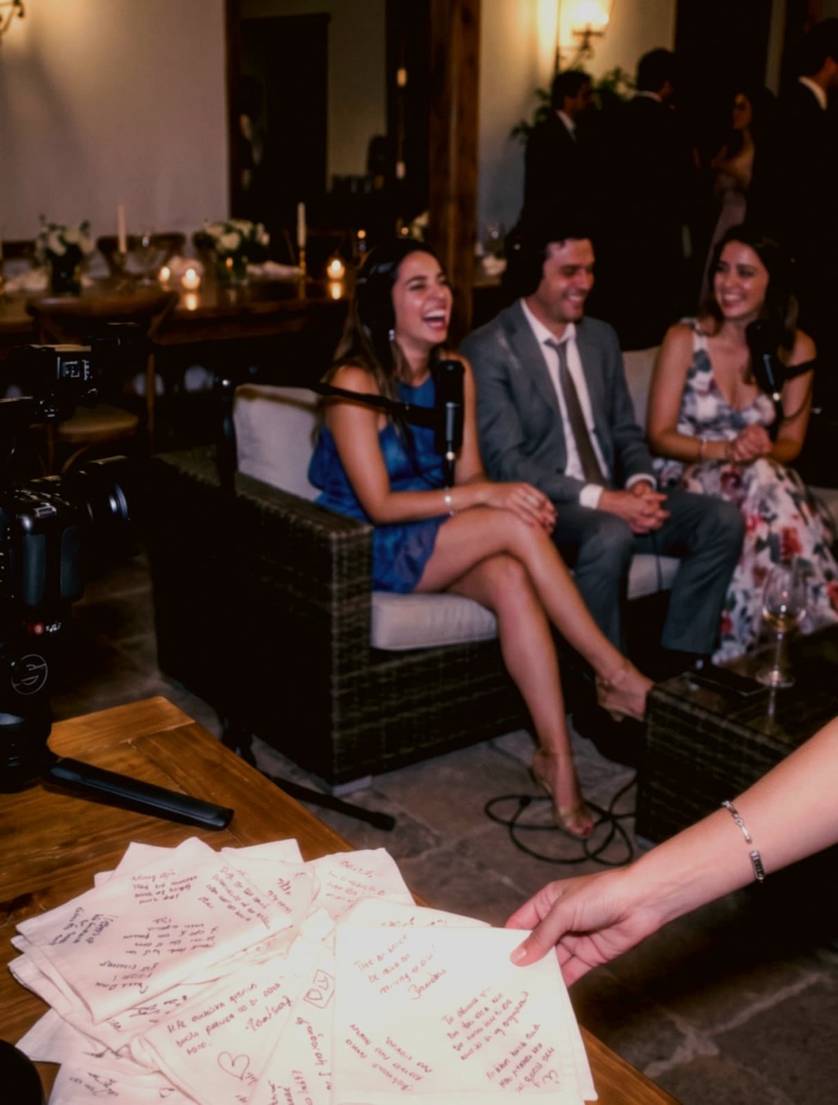 Servilletas con preguntas escritas a mano frente a un grupo de invitados en el lounge — recreación del ambiente Speak Now.